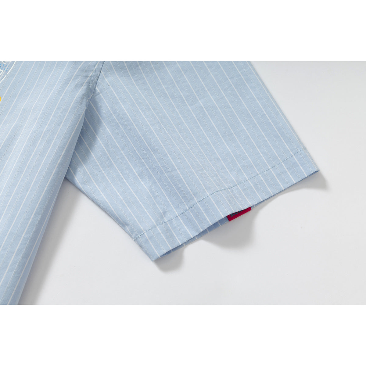 Close-up of a light blue pinstriped shirt sleeve hem and stitching.