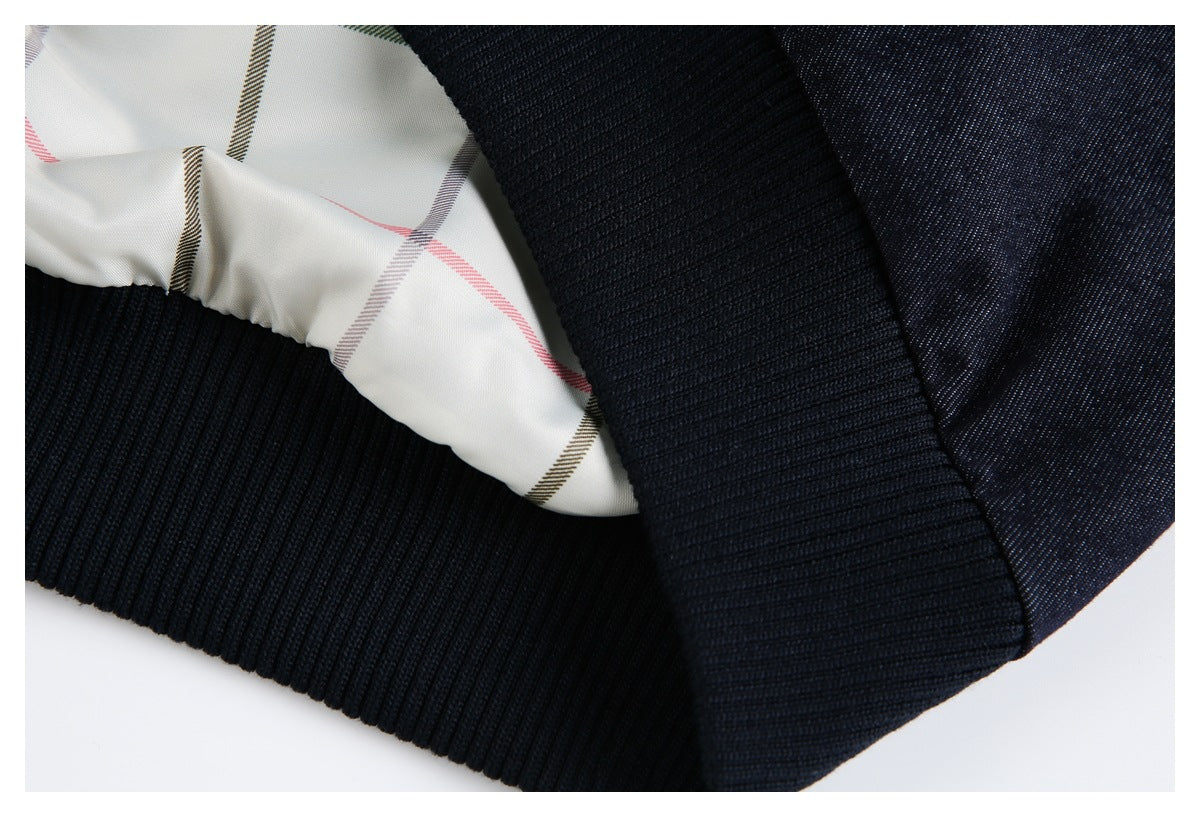 Close-up of a dark navy garment's black ribbed hem and white lining with colored plaid stripes.