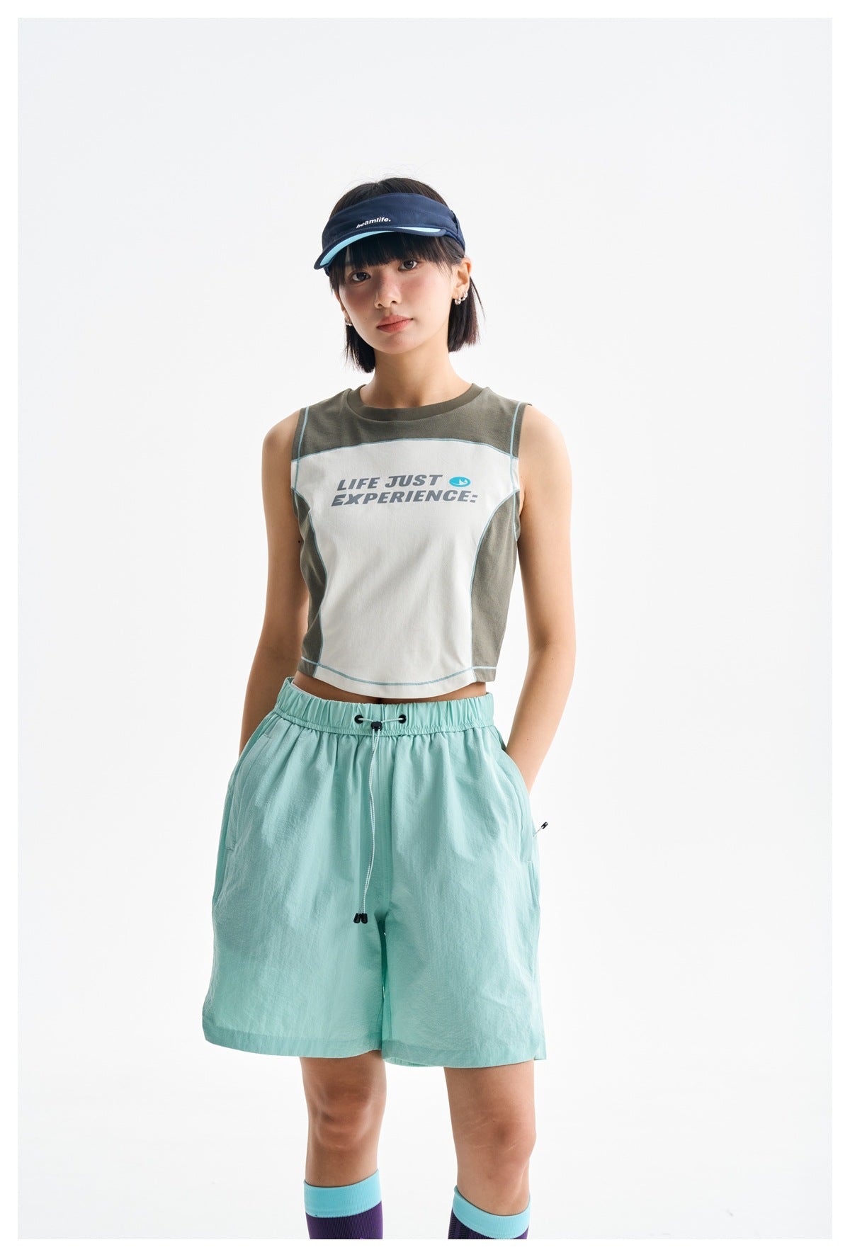 Model wearing a color-block sleeveless crop top and loose mint-green drawstring shorts, shown from the front.