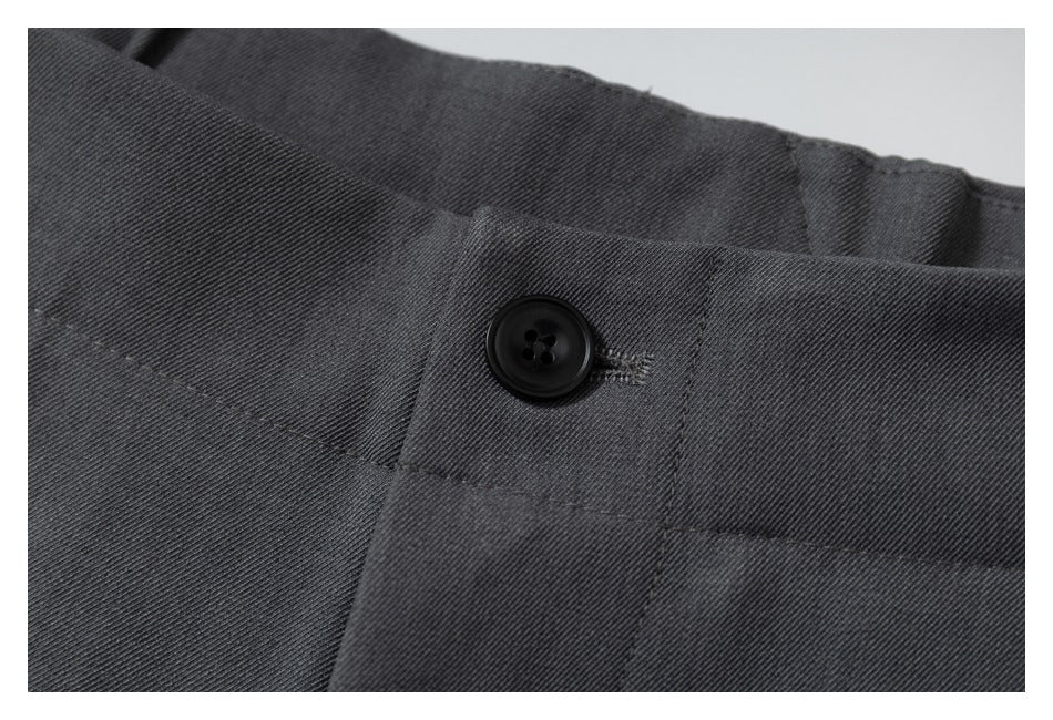 Close-up of the dark charcoal trouser waistband and black button fastening.