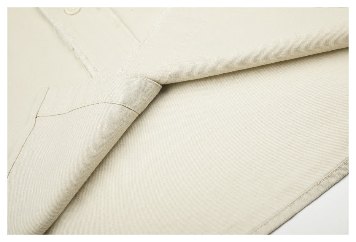 Close-up of ivory shirt fabric, stitching, and overlapping folded panels.