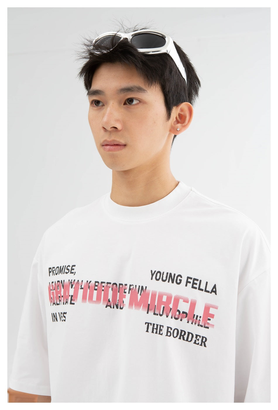 Close view of a model wearing a white T-shirt with layered black and red text across the chest.