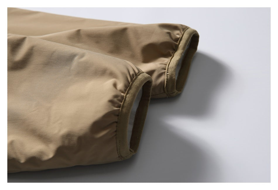 Close-up of a tan garment's gathered sleeve cuffs with darker bound edging.