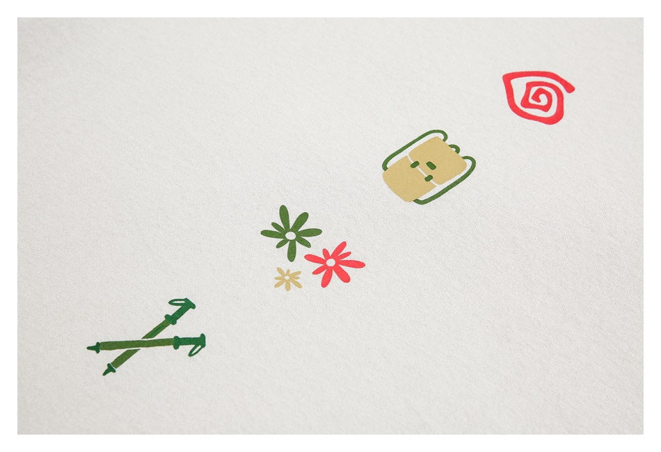 Close-up of scattered green, red, and gold graphics on off-white fabric, including flowers and small icons.