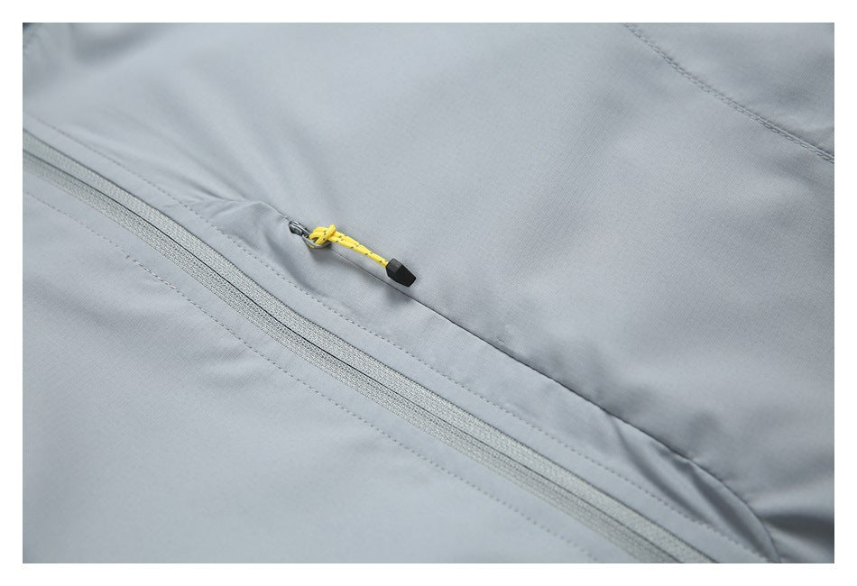 Close-up of a yellow zipper pull and seam on the gray jacket.