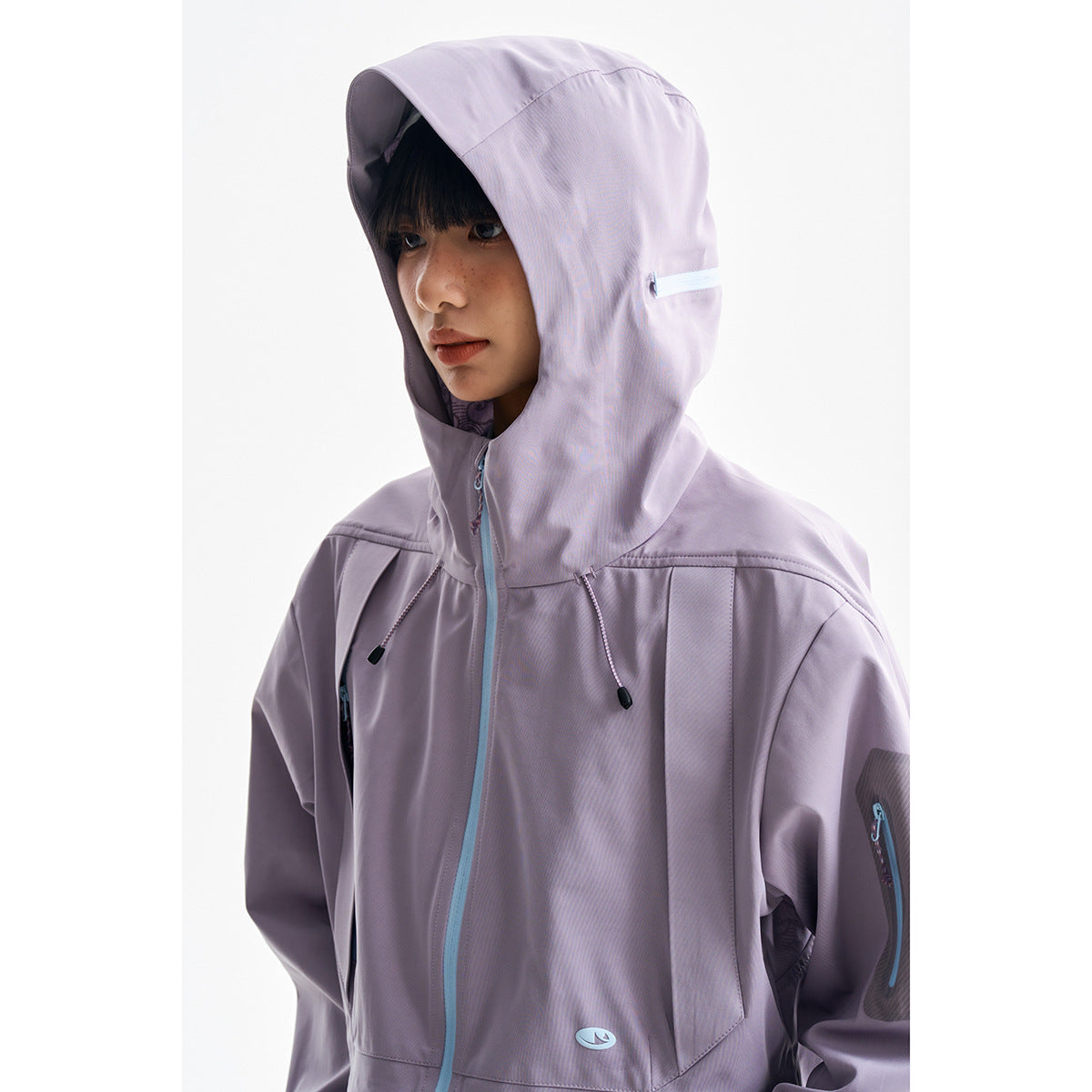 Close-up of a model wearing a lavender hooded jacket with aqua zippers and drawcords.