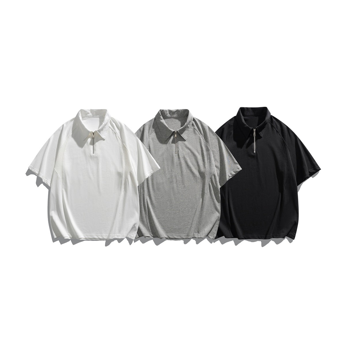 Three short-sleeve collared quarter-zip tops shown together in white, heather gray, and black.