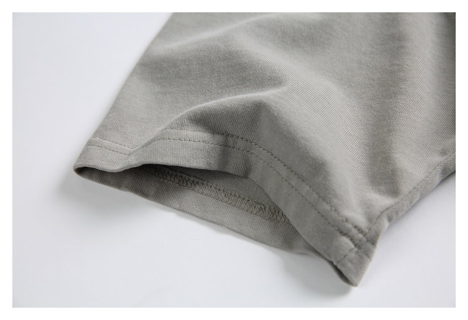 Close-up of the gray T-shirt sleeve hem, showing the stitching and overlocked underside.