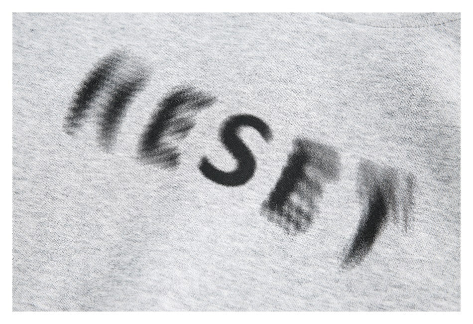 Close-up of a blurred black graphic printed on light heather-gray fabric.