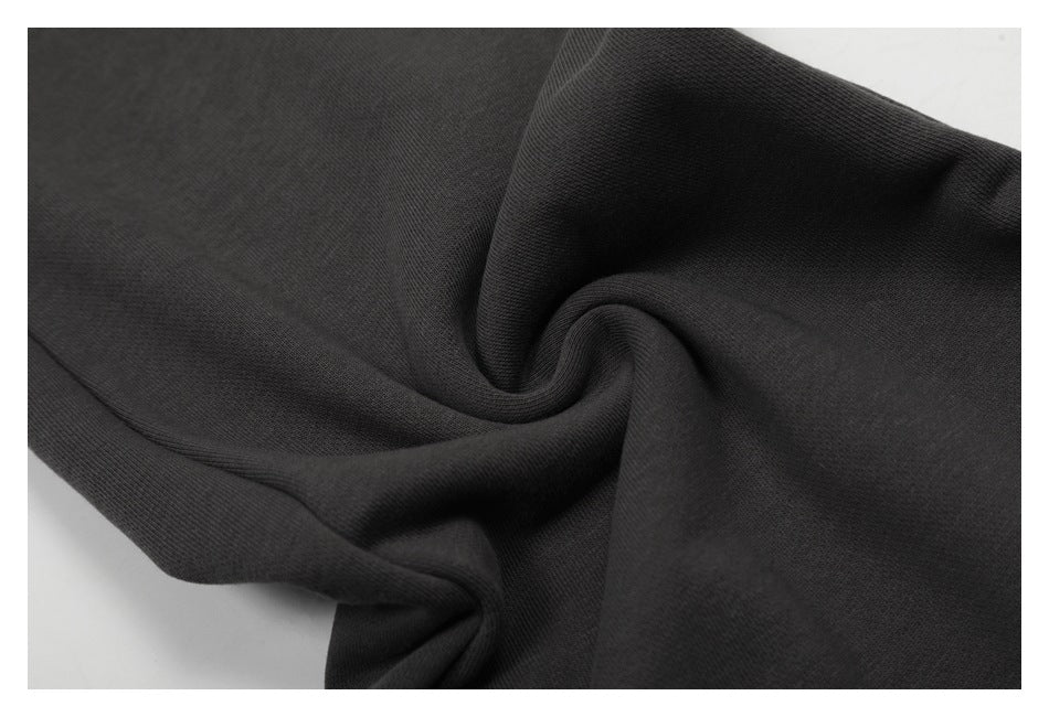 Close-up of charcoal pant fabric gathered into folds, showing its surface texture.