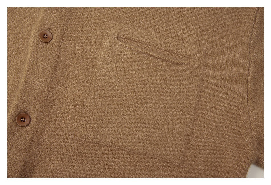 Close-up of the tan knit sweater's chest pocket and brown buttons.