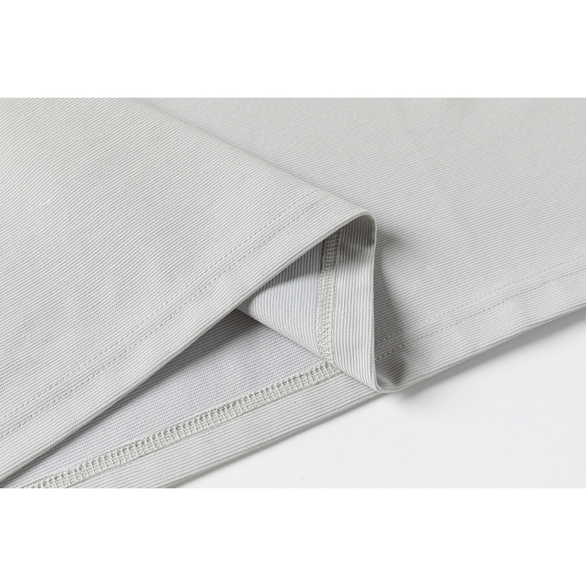 Close-up of the light gray polo shirt's folded hem and overlock stitching.