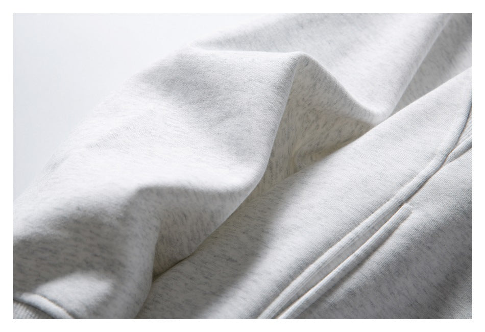Close-up of light gray hoodie fabric folds and a section of the zipper.