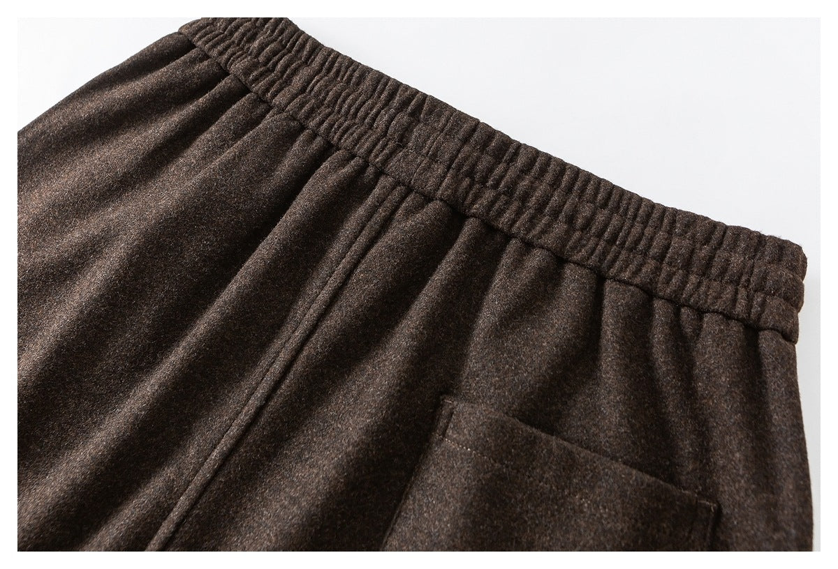 Close-up of dark brown pants showing the gathered waistband, drawcord and patch pocket.