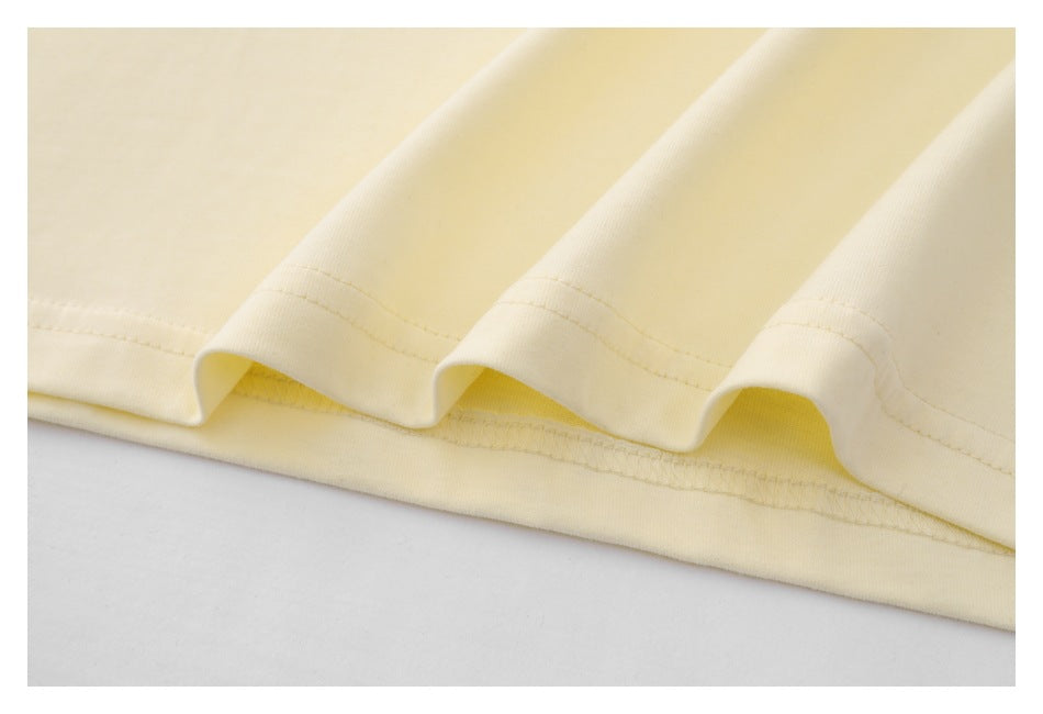 Close-up of the cream shirt's folded lower hem and parallel stitching.
