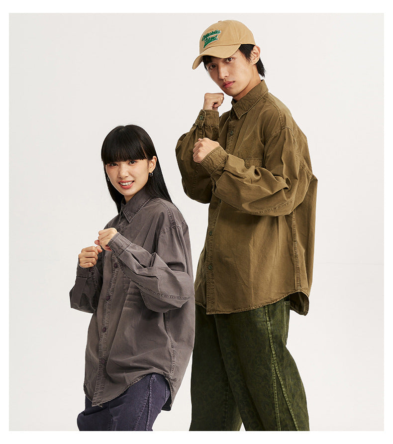Two models pose in oversized gray and olive-brown button-up shirts; the man wears a tan embroidered cap.