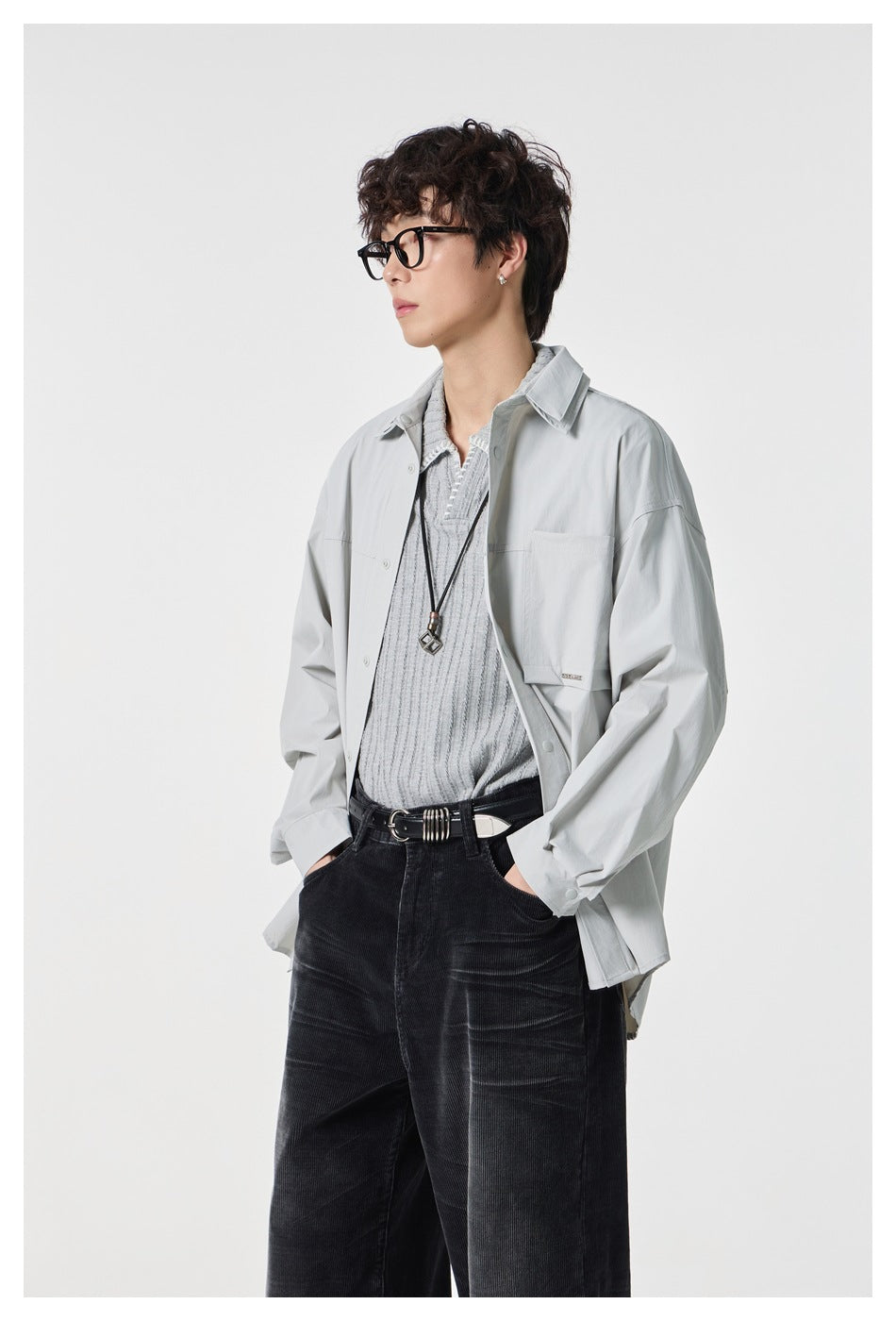 Model wearing a light gray oversized button-front shirt over a gray knit top, shown from the waist up.
