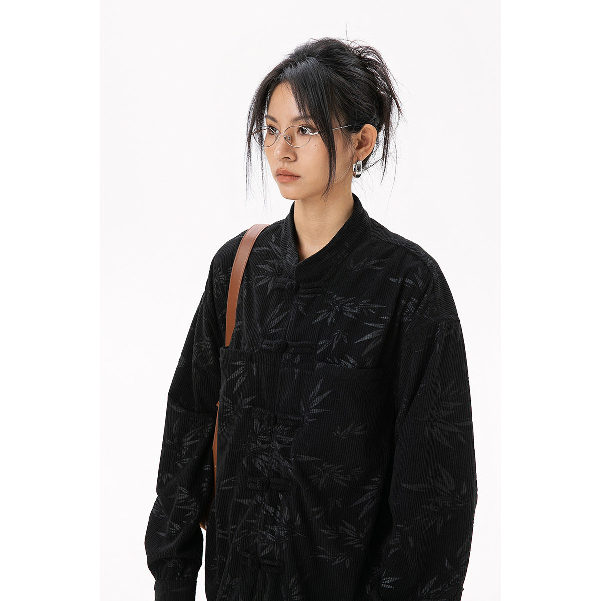 Close view of a model wearing a black bamboo-patterned jacket with frog closures.
