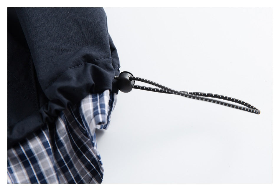 Close-up of a navy garment cuff with a black drawcord toggle and blue-gray plaid lining.