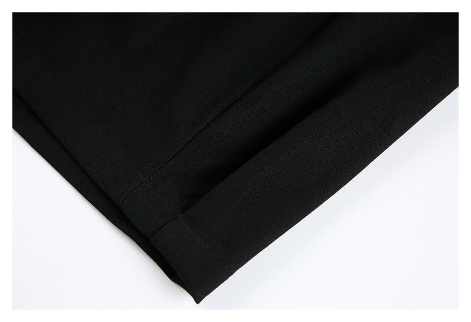 Close-up of the folded hem and seam on black trousers against a white background.