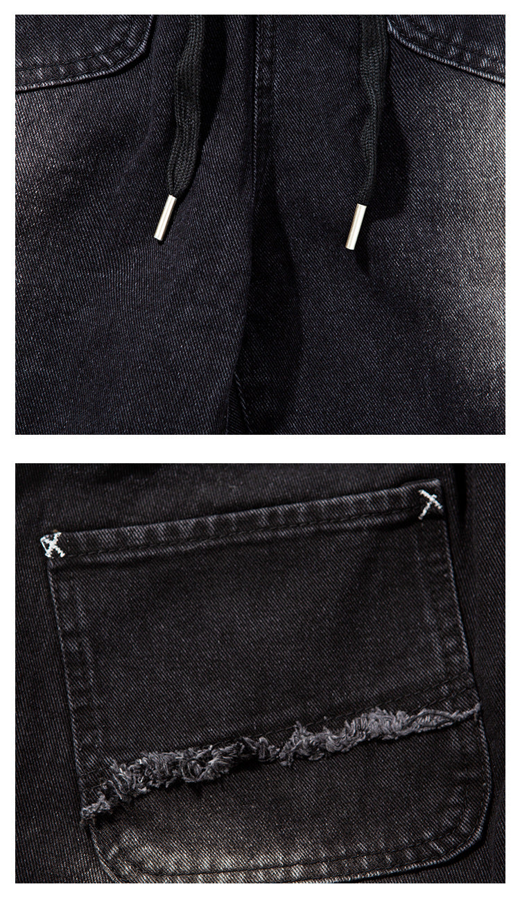Close-up of black denim joggers showing drawstrings with metal tips and a pocket with a frayed edge.