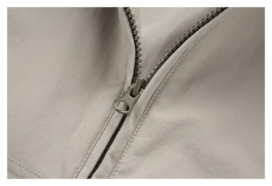 Close-up of the jacket's front zipper and pull against light taupe fabric.