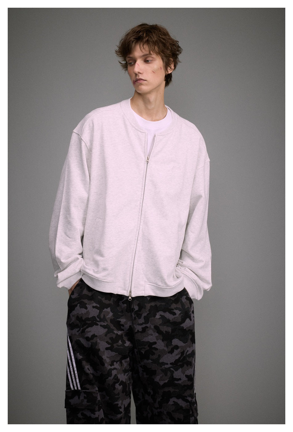 Close-up of model in a light heather gray zip-front jacket with ribbed collar and hem over a white tee