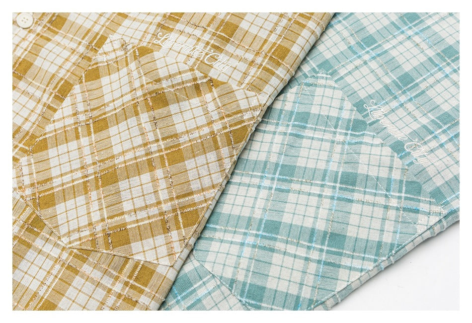 Close-up of mustard and teal plaid shirts showing matching rounded patch pockets and white script embroidery.
