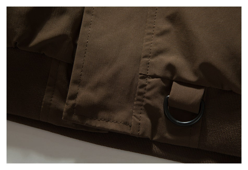 Close-up of a brown garment hem with a black D-ring and textured elastic band.