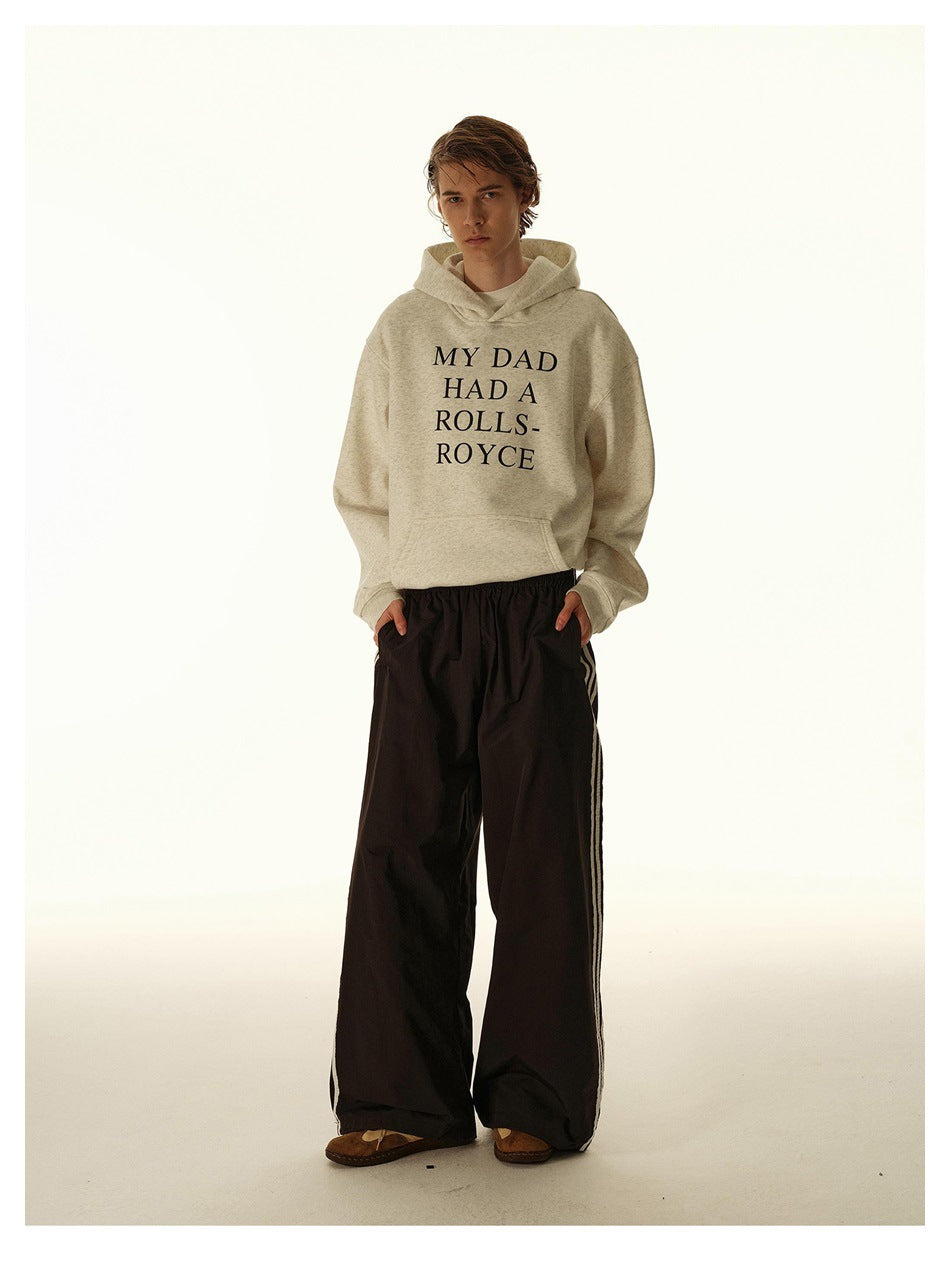 Model wearing black wide-leg pants with white side stripes, a cream hoodie and brown shoes