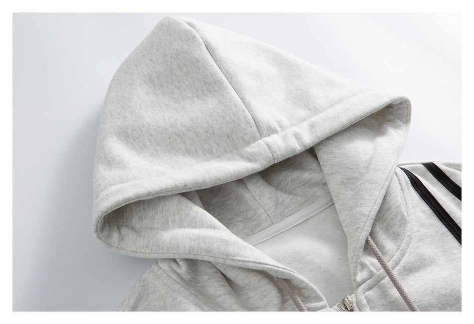 Close-up of a light gray marl hoodie’s hood, drawstrings, zipper, and black shoulder stripes.