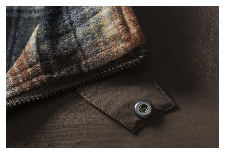 Close-up of a brown garment’s zipper, snap tab, and multicolored plaid lining.