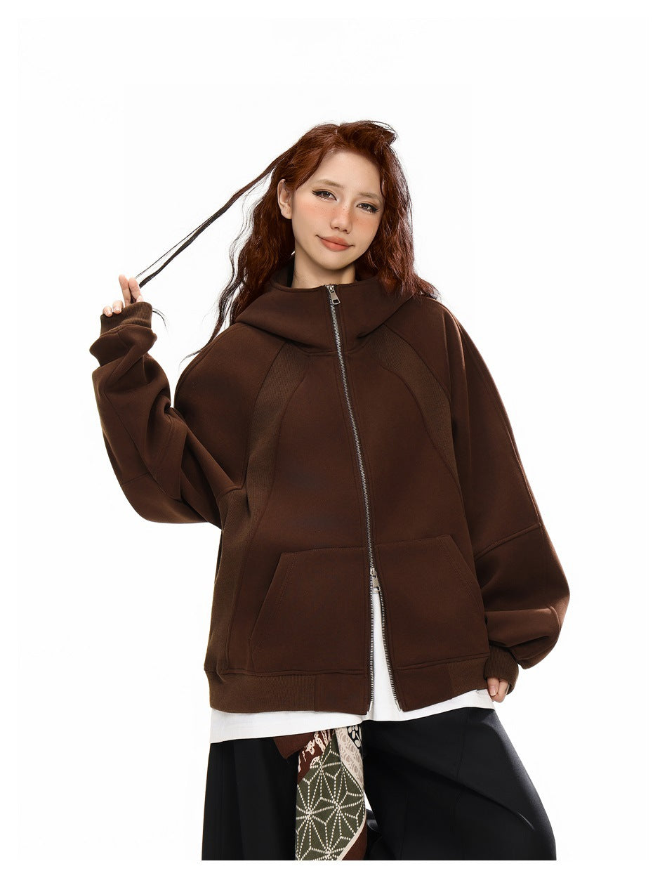 Front view of a model wearing a zipped dark brown hooded jacket with oversized sleeves and two front pockets.