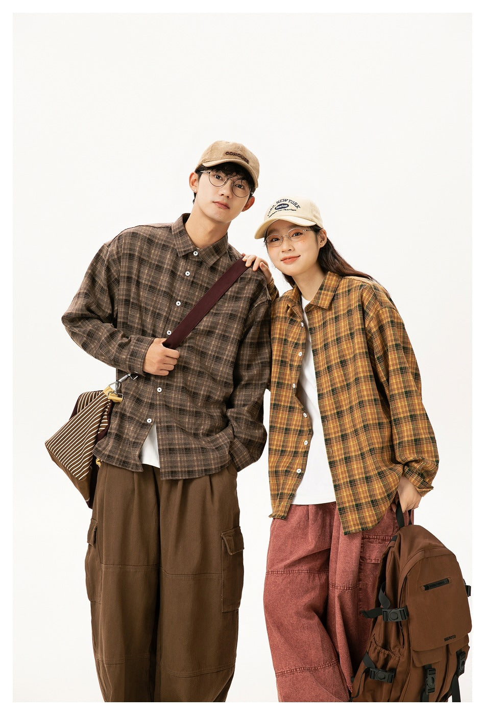 Two models wear oversized plaid button-up shirts: brown on the man and mustard yellow on the woman.