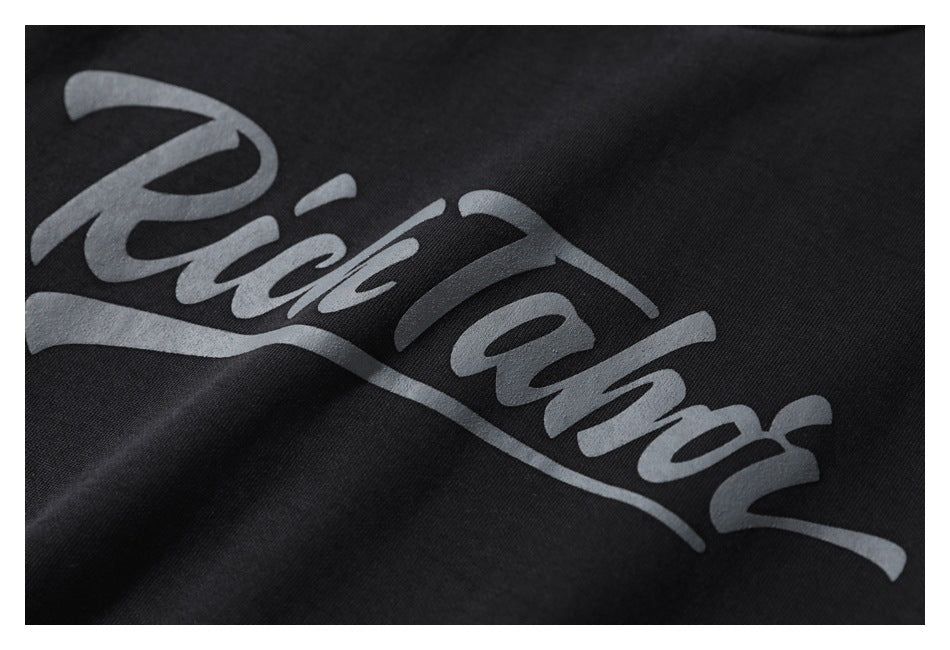 Close-up of a black garment with large gray cursive lettering printed across the fabric.