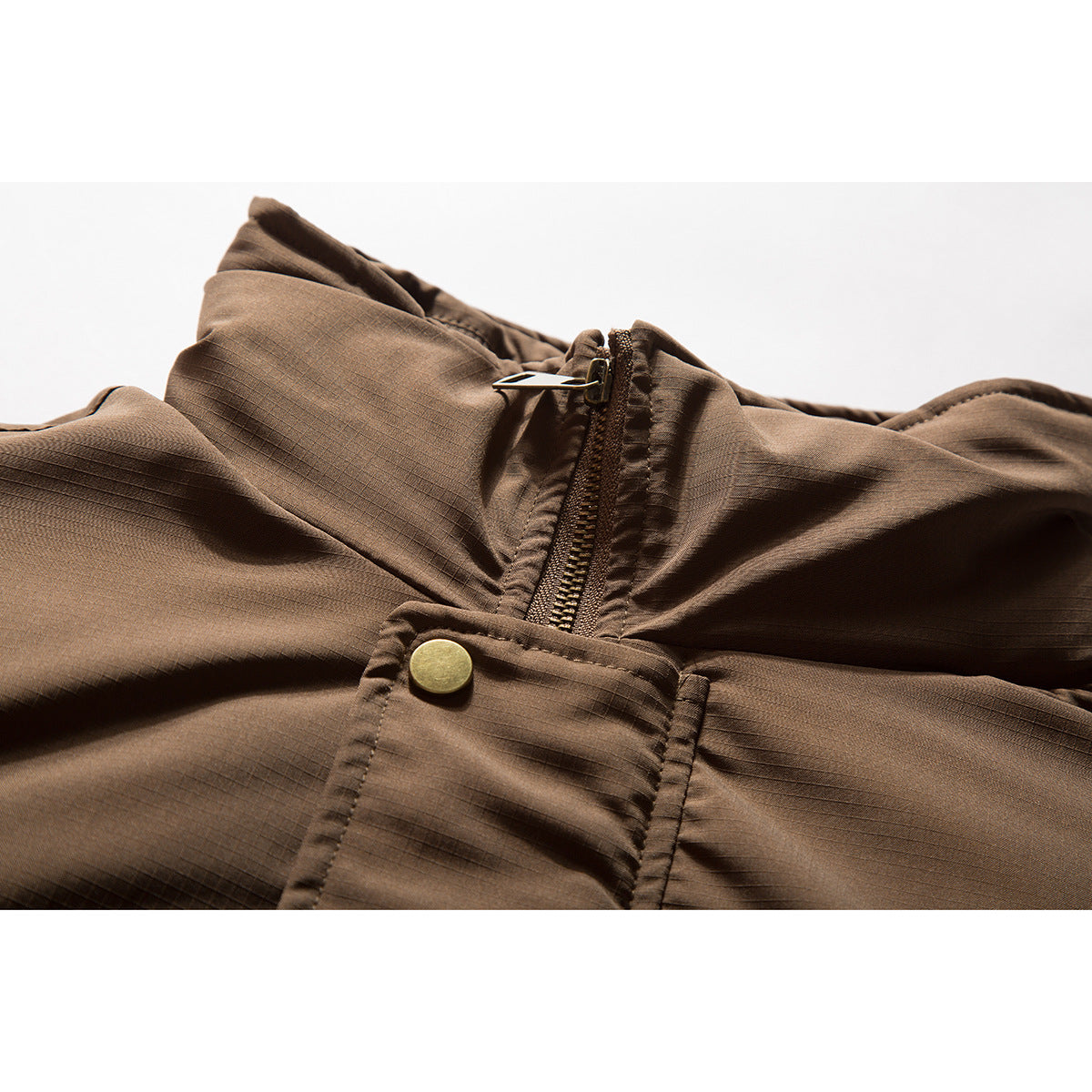 Close-up of a brown jacket collar, zipper, snap-button storm flap, and subtle grid texture.