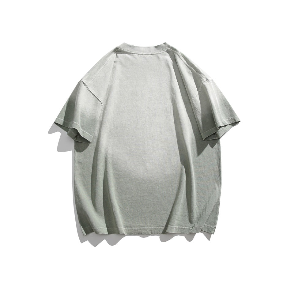 Back view of a plain oversized pale sage-green short-sleeve T-shirt laid flat on white.