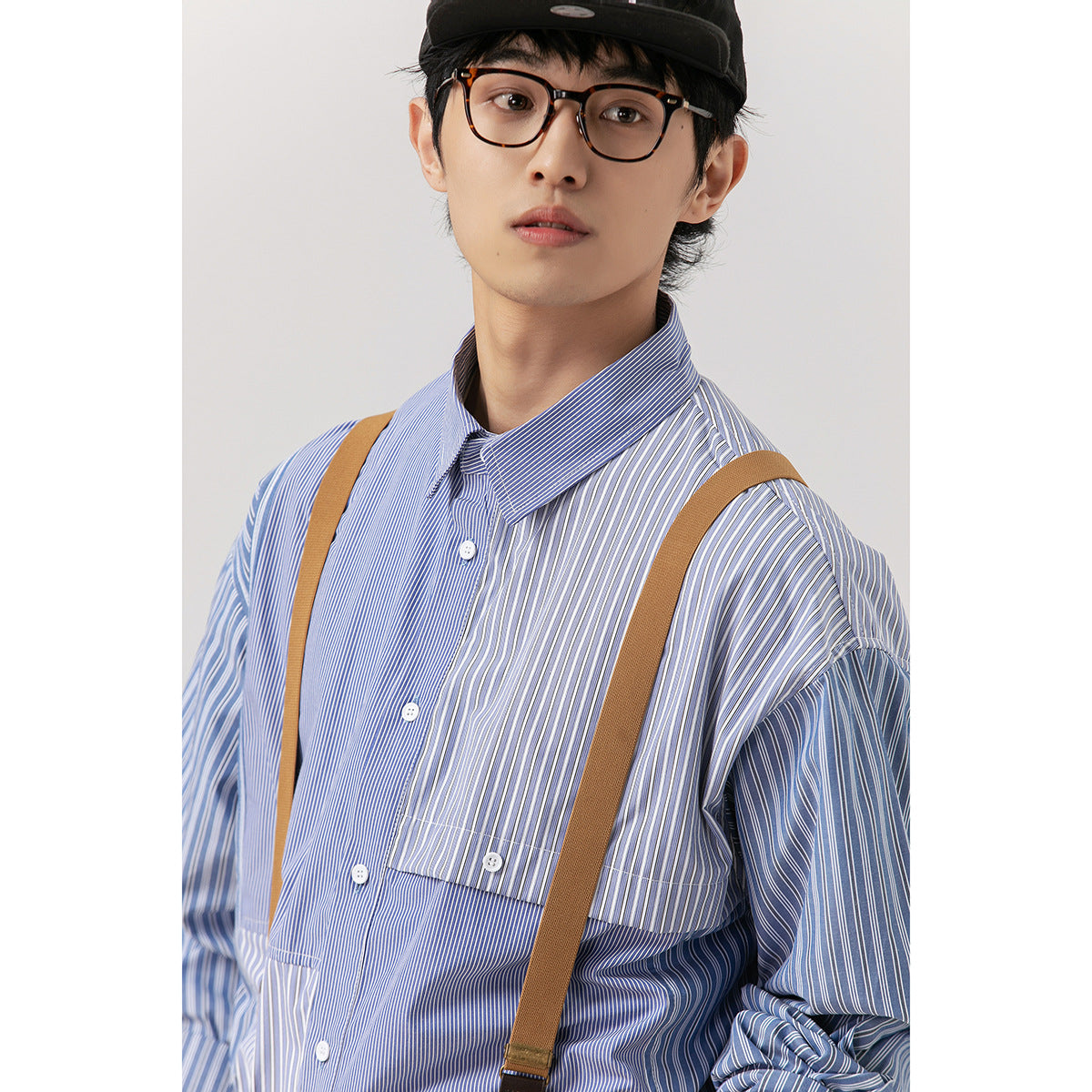 Close view of a model wearing a blue-and-white striped patchwork button-up shirt with a chest pocket.