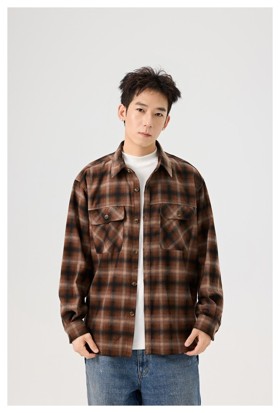 Man wearing a brown plaid shirt with chest flap pockets open over a white top, front view from the thighs up