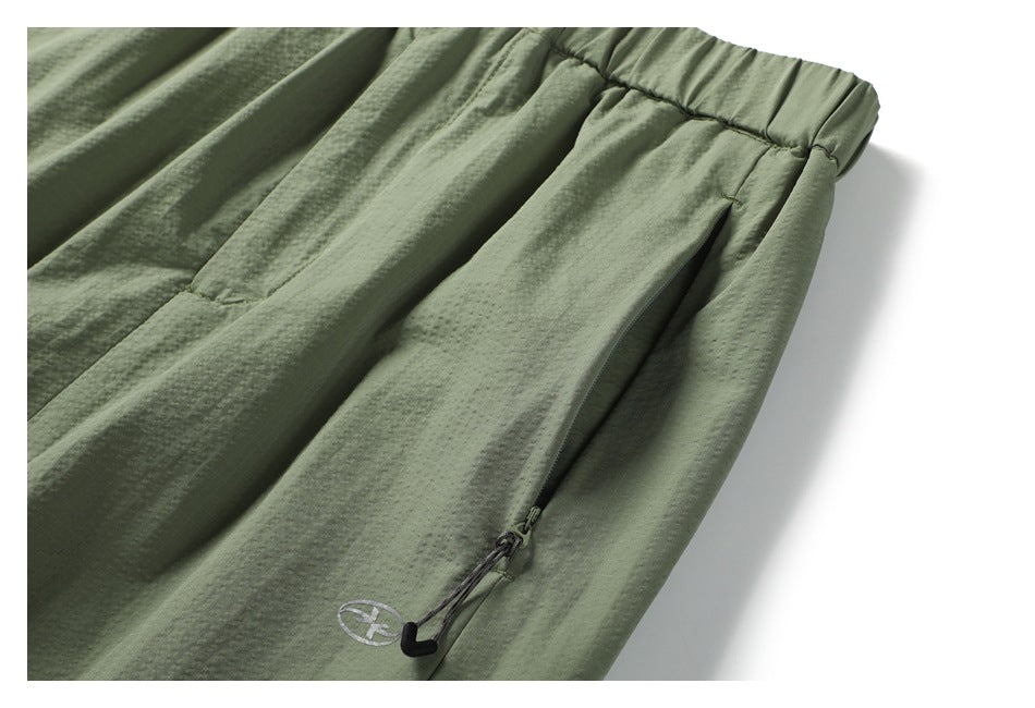Close-up of the sage green skirt's elastic waistband, textured fabric and zip pocket with cord pull.