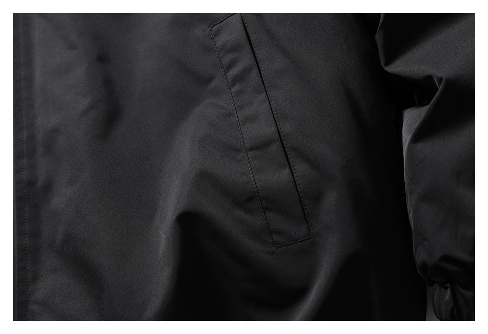 Close-up of a black jacket’s vertical welt pocket and sleeve cuff.