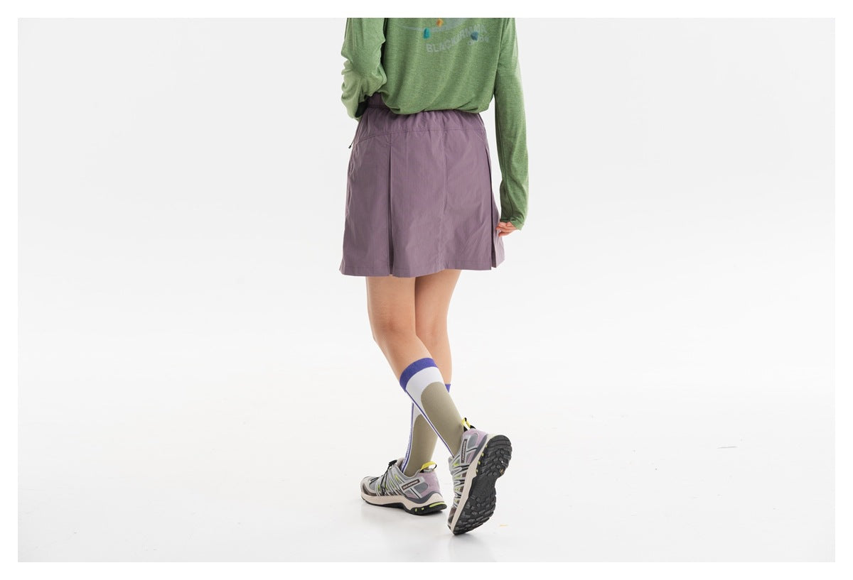 Back view of a model wearing a muted mauve skirt with an elastic waistband and a green top.