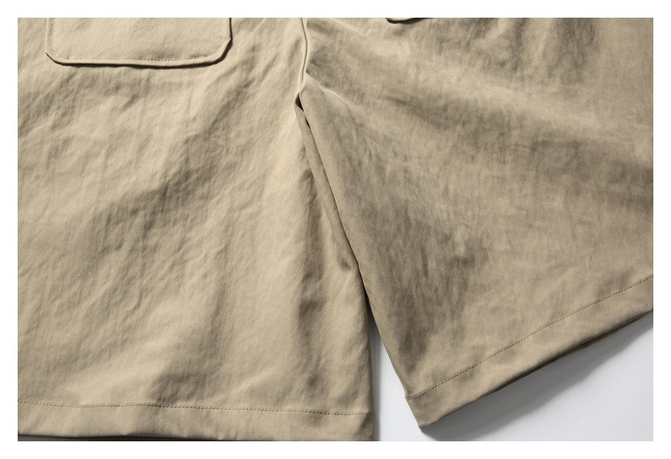 Close-up of beige garment fabric showing a patch pocket, stitching, and a finished hem.