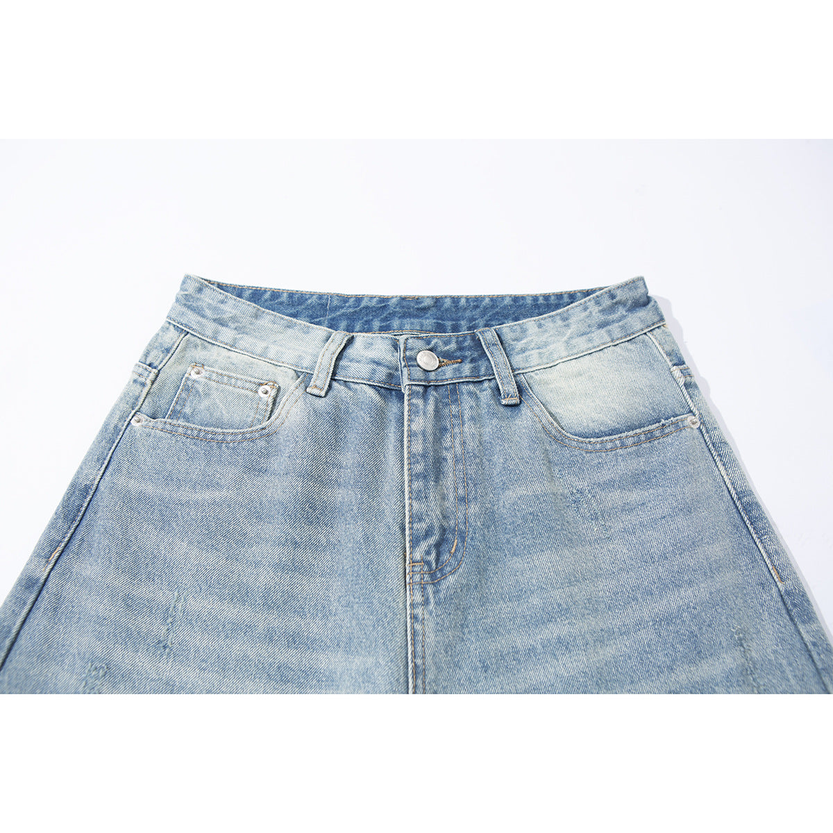Close-up of light-wash blue jeans showing the front waistband, button, belt loops and pockets.