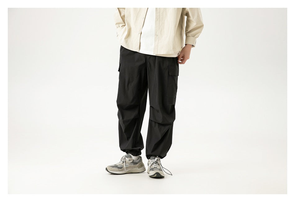 Front view of a model wearing loose black cargo pants with side pockets and gathered cuffs.