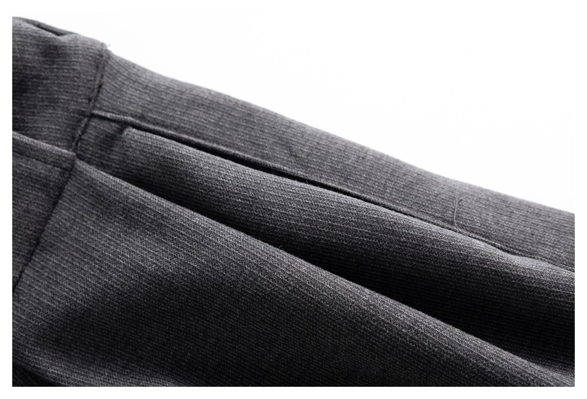 Close-up of charcoal gray trouser fabric and a slanted pocket opening.