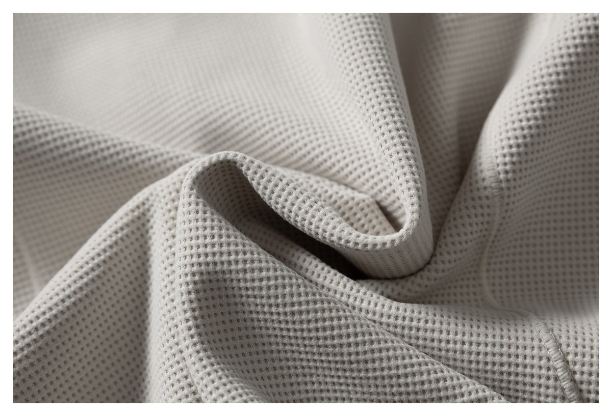 Macro view of the pale gray waffle-knit fabric, showing its raised square texture and stitching.