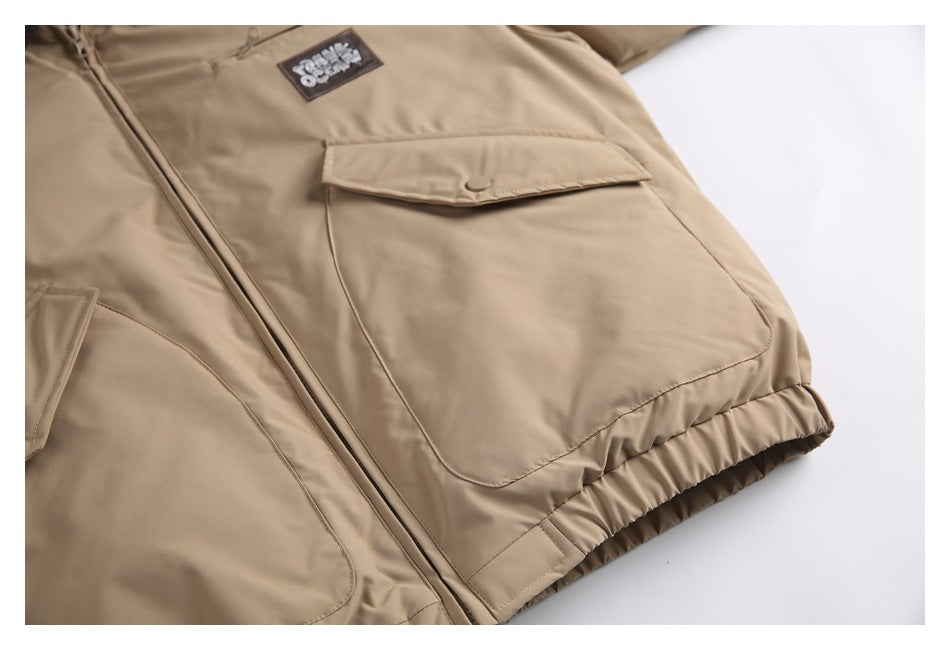 Partial front view of a tan jacket with a center zipper, large flap and lower pockets, and an elastic hem.