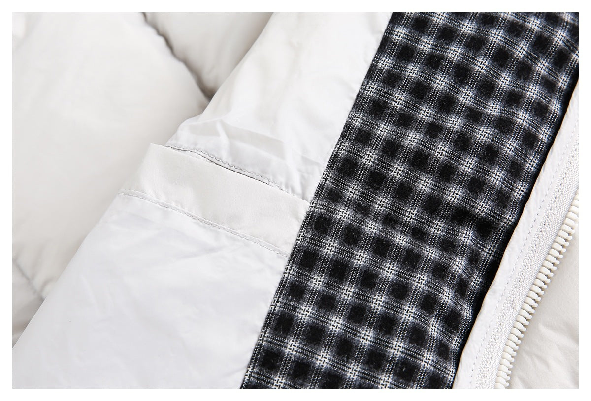 Close-up of an off-white padded jacket with a black-and-white checked inner panel beside the zipper.