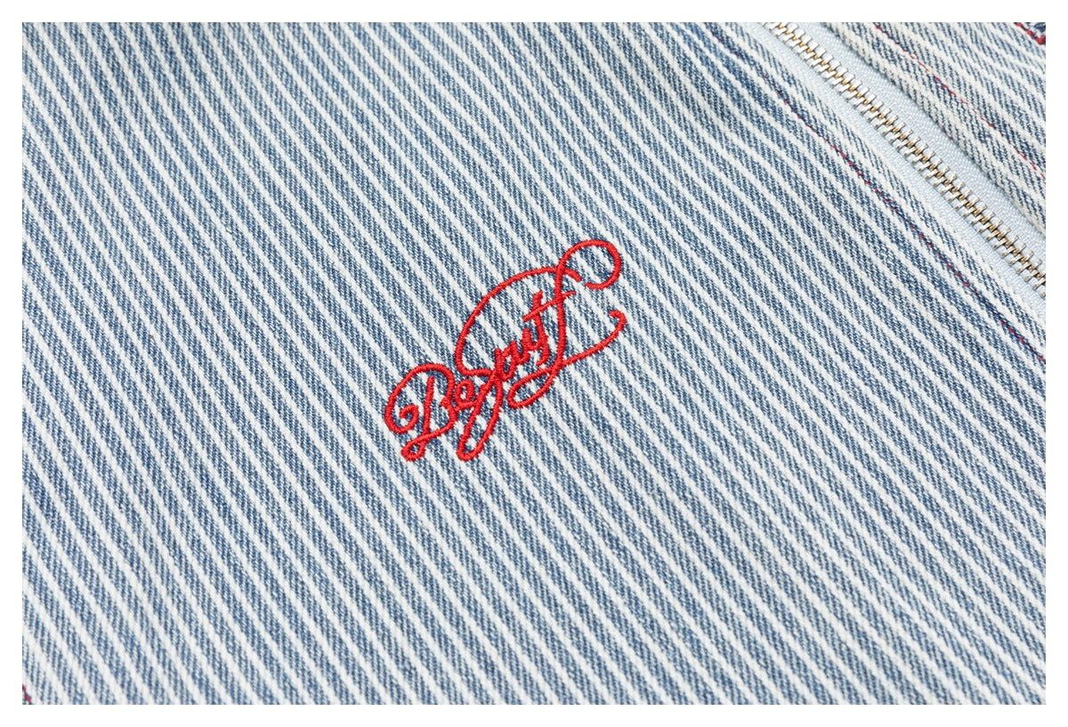 Close-up of blue-and-white diagonal stripes with red script embroidery and a metal zipper.